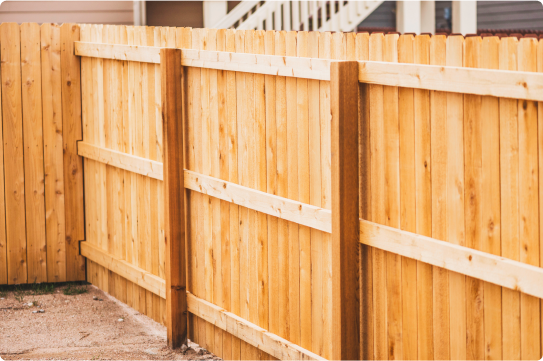 A newly installed wooden privacy fence with vertical planks, showing the posts and horizontal support rails.