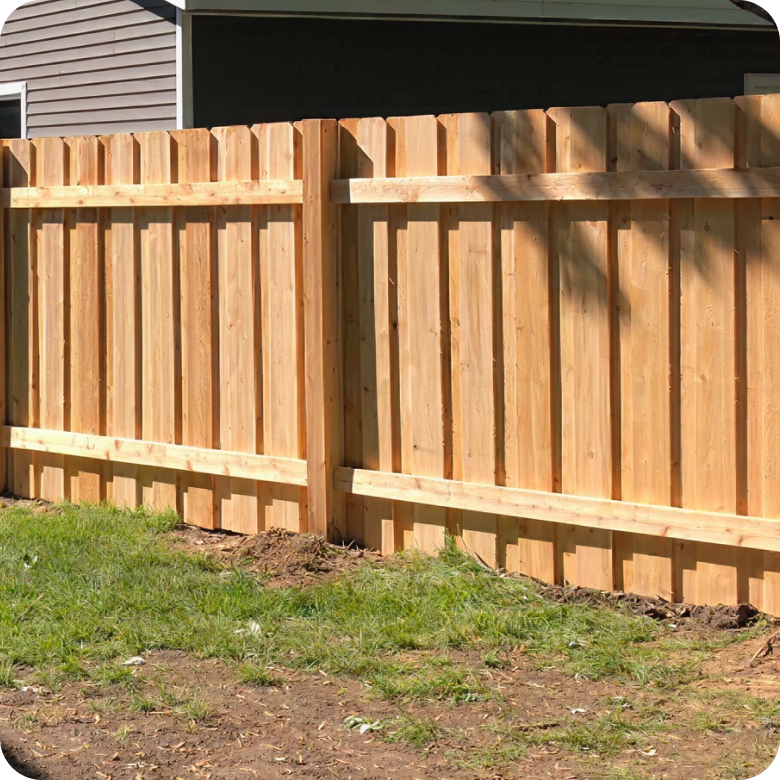 A traditional wooden privacy fence with vertical planks in a backyard.